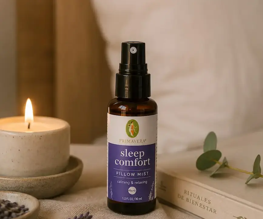 Brisa para almohada Sleep Comfort de Primavera sobre una mesa de madera con una vela, lavanda y un libro en un ambiente cálido y relajante.